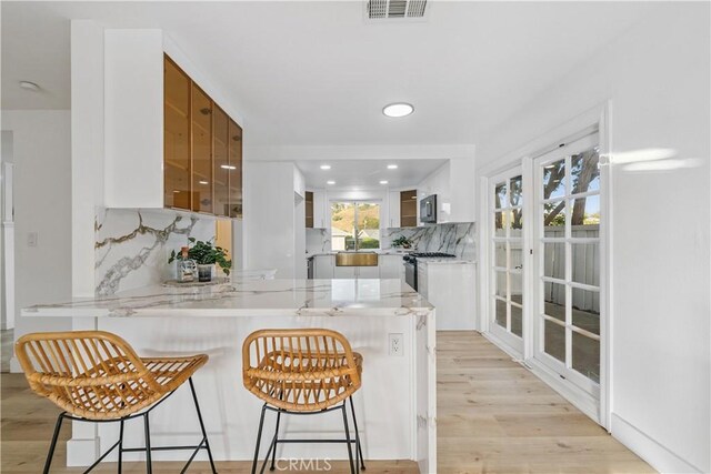 24135 Las Naranjas Dr, Laguna Niguel, CA 92677 - kitchen with a peninsula, backsplash, white cabinetry, glass insert cabinets, and a kitchen breakfast bar