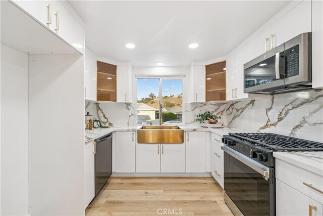 24135 Las Naranjas Dr, Laguna Niguel, CA 92677 - kitchen featuring appliances with stainless steel finishes, backsplash, white cabinetry, light stone countertops, and light wood-type flooring