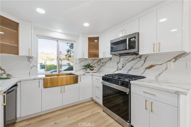 24135 Las Naranjas Dr, Laguna Niguel, CA 92677 - kitchen with stainless steel appliances, white cabinets, light stone countertops, backsplash, and light wood-type flooring