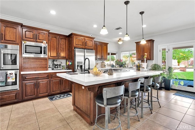 19420 Red Feather Rd, Apple Valley, CA 92307 - kitchen featuring stainless steel appliances, light countertops, an island with sink, light tile patterned floors, and a kitchen bar