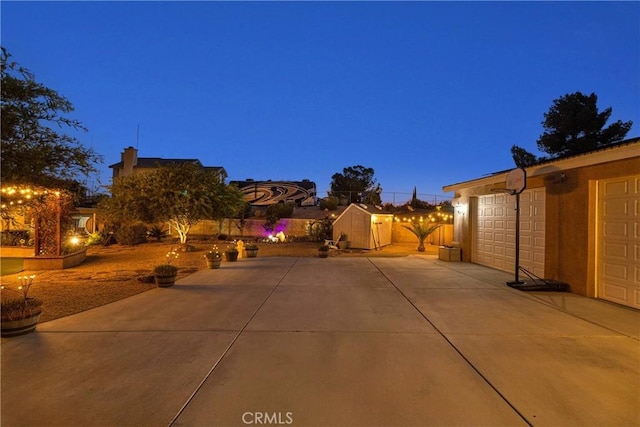 19420 Red Feather Rd, Apple Valley, CA 92307 - patio at night featuring a garage, concrete driveway, and a shed