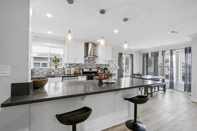 4903 Deeboyar Ave, Lakewood, CA 90712 - kitchen featuring wall chimney exhaust hood, appliances with stainless steel finishes, dark countertops, tasteful backsplash, and a kitchen bar