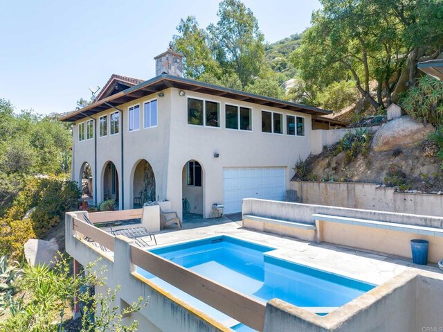 46920 Rainbow Canyon Rd, Temecula, CA 92592 - back of property featuring a garage, stucco siding, a chimney, and a hot tub