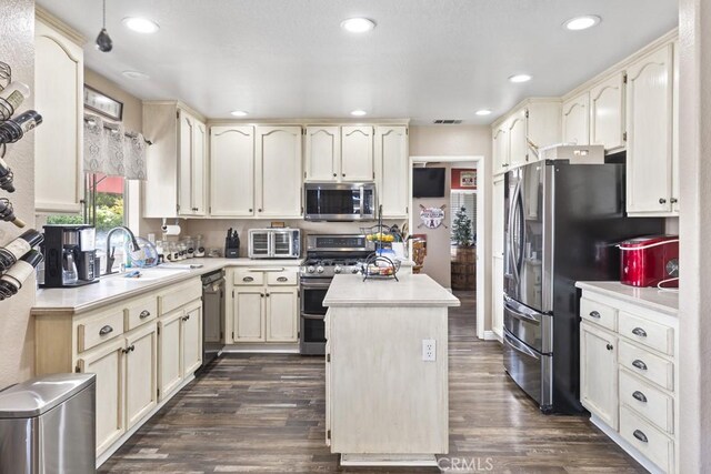 3025 Black Horse Dr, Ontario, CA 91761 - kitchen with appliances with stainless steel finishes, light countertops, dark wood-style flooring, a kitchen island, and cream cabinetry