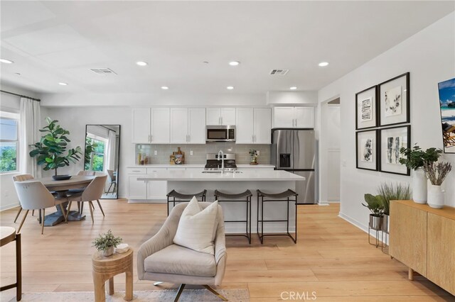 305 Blackrock, Lake Forest, CA 92610 - kitchen with stainless steel appliances, light countertops, white cabinetry, backsplash, and light wood finished floors