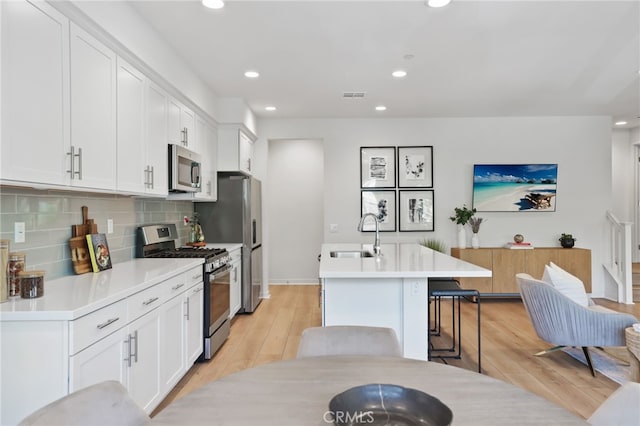 305 Blackrock, Lake Forest, CA 92610 - kitchen featuring appliances with stainless steel finishes, a kitchen island with sink, tasteful backsplash, white cabinetry, and recessed lighting