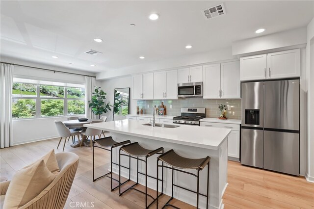 305 Blackrock, Lake Forest, CA 92610 - kitchen with appliances with stainless steel finishes, light countertops, a kitchen breakfast bar, backsplash, and white cabinets