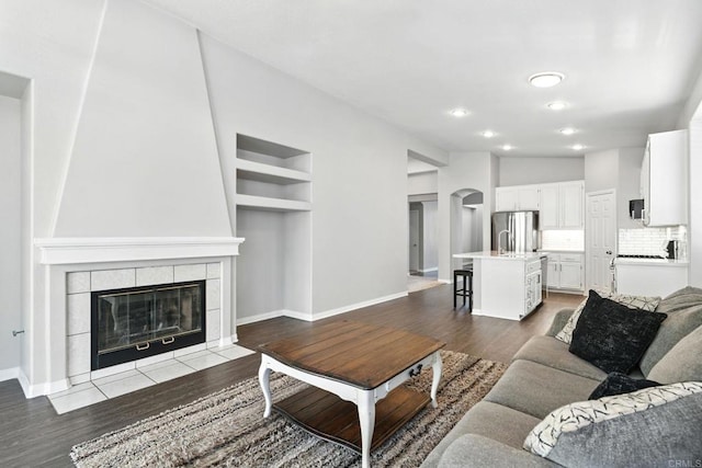 46076 Via Ln, Colorada, Temecula, CA 92592 - living area with arched walkways, wood finished floors, a tiled fireplace, recessed lighting, and built in features