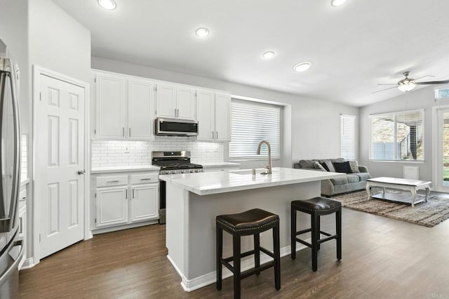 46076 Via Ln, Colorada, Temecula, CA 92592 - kitchen with appliances with stainless steel finishes, dark wood-style floors, open floor plan, tasteful backsplash, and a breakfast bar