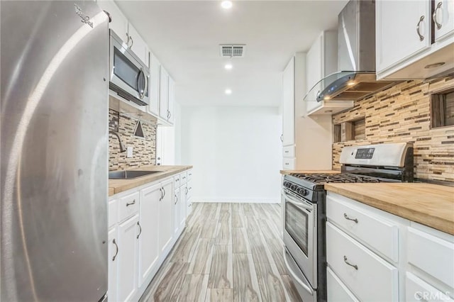 38876 Foxholm Dr, Palmdale, CA 93551 - kitchen featuring appliances with stainless steel finishes, wall chimney exhaust hood, tasteful backsplash, wooden counters, and recessed lighting