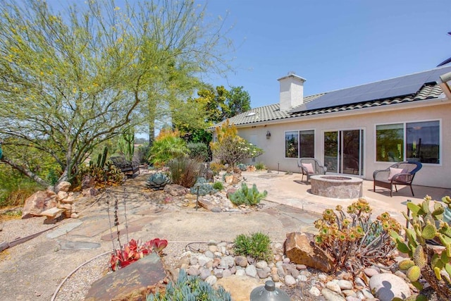 2149 Gamble Pl, Escondido, CA 92029 - rear view of house with a fire pit, a chimney, a patio area, roof mounted solar panels, and stucco siding