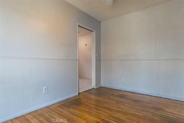 15300 Mayall St, San Fernando, CA 91345 - unfurnished room with wood finished floors, a wainscoted wall, and a textured ceiling