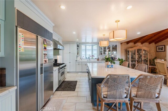 26767 Shadow Wood Dr, Rancho Palos Verdes, CA 90275 - kitchen with high quality appliances, wall chimney exhaust hood, recessed lighting, decorative light fixtures, and glass insert cabinets