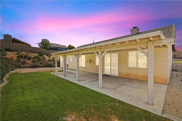 42158 Valley Vista Dr, Lancaster, CA 93536 - back of property at dusk featuring a chimney, a lawn, stucco siding, and a patio