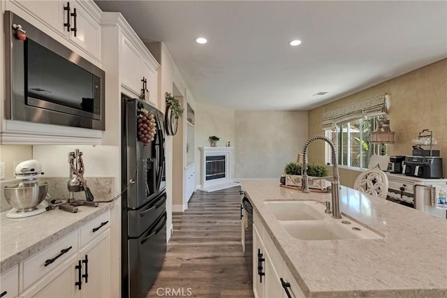 19639 Ellis Henry Ct, Newhall, CA 91321 - kitchen featuring stainless steel microwave, black refrigerator with ice dispenser, dark wood finished floors, a kitchen island with sink, and white cabinetry