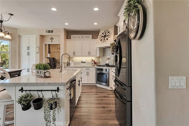 19639 Ellis Henry Ct, Newhall, CA 91321 - kitchen featuring black appliances, white cabinets, a kitchen breakfast bar, dark wood-type flooring, and a center island with sink