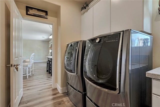 19639 Ellis Henry Ct, Newhall, CA 91321 - laundry room with washing machine and dryer, light wood-style flooring, and cabinet space