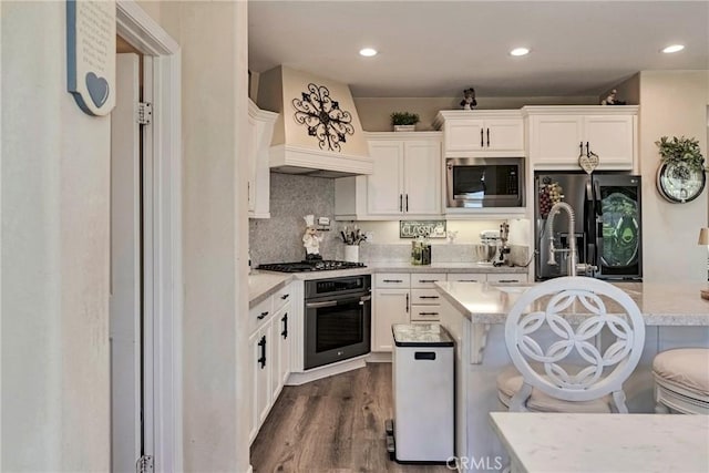 19639 Ellis Henry Ct, Newhall, CA 91321 - kitchen with appliances with stainless steel finishes, light countertops, white cabinets, a breakfast bar, and dark wood-style floors