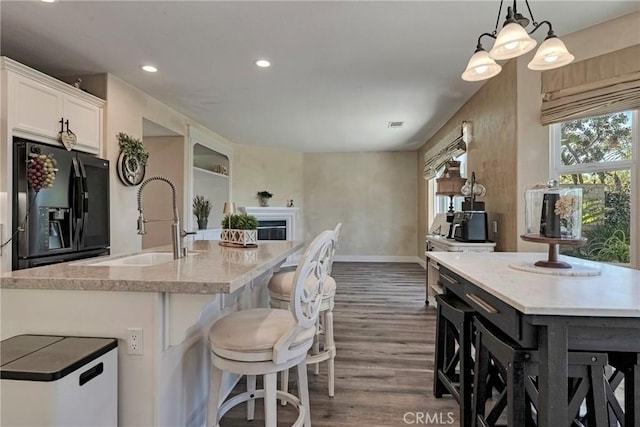 19639 Ellis Henry Ct, Newhall, CA 91321 - kitchen featuring black refrigerator with ice dispenser, a kitchen island with sink, dark wood-type flooring, white cabinetry, and recessed lighting
