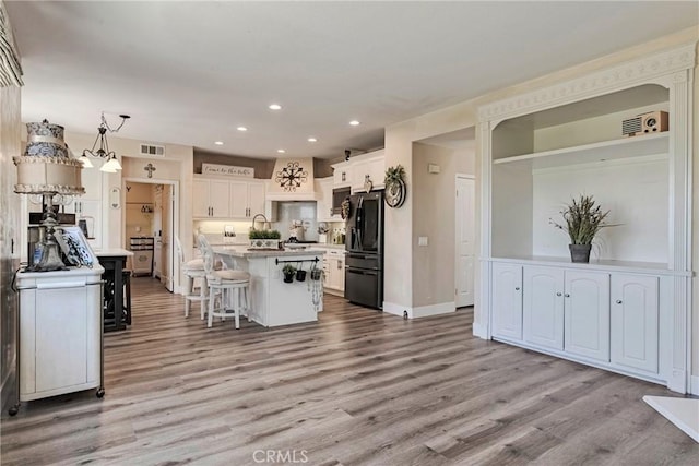 19639 Ellis Henry Ct, Newhall, CA 91321 - kitchen featuring black fridge, recessed lighting, wood finished floors, a breakfast bar, and white cabinets