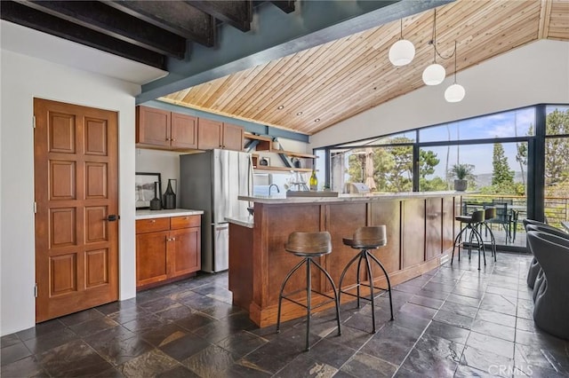 686 Diamond St, Laguna Beach, CA 92651 - kitchen with freestanding refrigerator, a kitchen bar, stone tile floors, wood ceiling, and brown cabinetry
