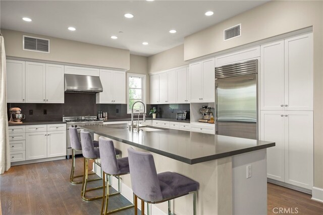 23500 Park Sorrento Unit H32, Calabasas, CA 91302 - kitchen featuring high end appliances, exhaust hood, dark countertops, decorative backsplash, and recessed lighting