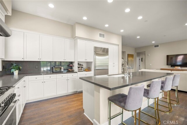 23500 Park Sorrento Unit H32, Calabasas, CA 91302 - kitchen with stainless steel built in refrigerator, stove, dark countertops, dark wood finished floors, and white cabinets