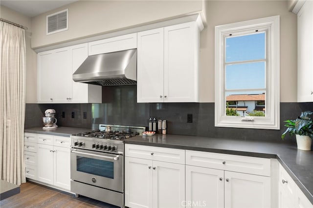 23500 Park Sorrento Unit H32, Calabasas, CA 91302 - kitchen with wall chimney exhaust hood, high end range, dark countertops, and tasteful backsplash