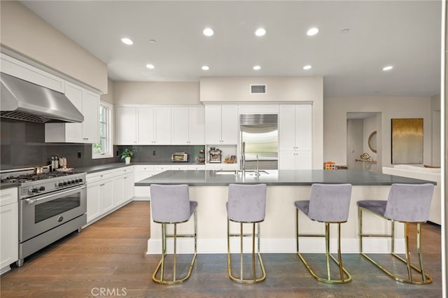 23500 Park Sorrento Unit H32, Calabasas, CA 91302 - kitchen with high end appliances, range hood, a breakfast bar, dark countertops, and recessed lighting