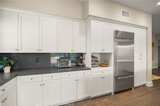 23500 Park Sorrento Unit H32, Calabasas, CA 91302 - kitchen with built in fridge, dark wood finished floors, dark countertops, and tasteful backsplash