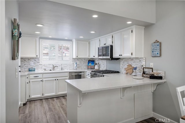 309 Sequoia St Unit 3, Morro Bay, CA 93442 - kitchen with stainless steel appliances, a peninsula, light wood-type flooring, white cabinets, and recessed lighting