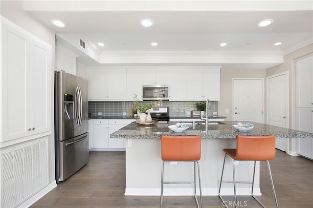 402 Maravilla Ln, Brea, CA 92823 - kitchen with appliances with stainless steel finishes, crown molding, white cabinets, backsplash, and a kitchen breakfast bar