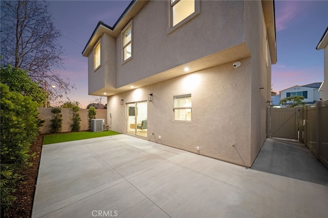 16229 Orizaba Ave, Paramount, CA 90723 - back of house at dusk featuring stucco siding, a gate, a fenced backyard, and a patio