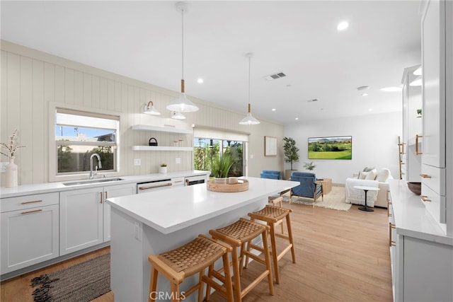 16229 Orizaba Ave, Paramount, CA 90723 - kitchen with open floor plan, a kitchen island, a breakfast bar area, light wood finished floors, and light countertops