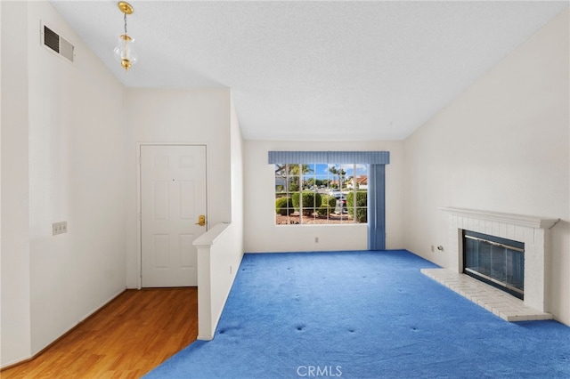 26293 Potomac Dr, Menifee, CA 92586 - unfurnished living room with a brick fireplace, carpet floors, and wood finished floors