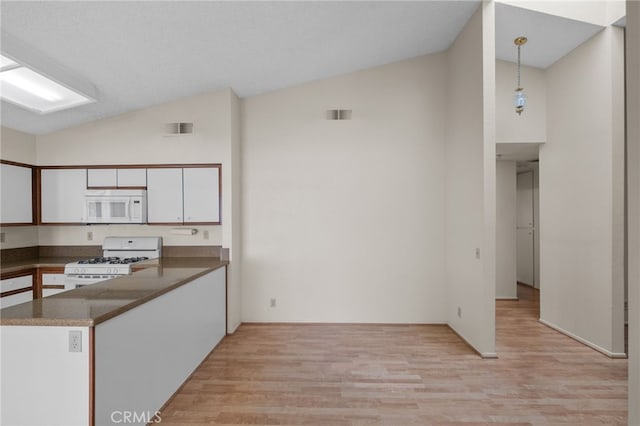 26293 Potomac Dr, Menifee, CA 92586 - kitchen with white appliances, dark countertops, white cabinets, light wood finished floors, and a peninsula