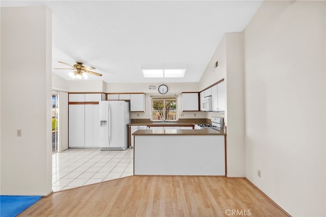 26293 Potomac Dr, Menifee, CA 92586 - kitchen with white appliances, white cabinets, a peninsula, a ceiling fan, and light wood-style floors