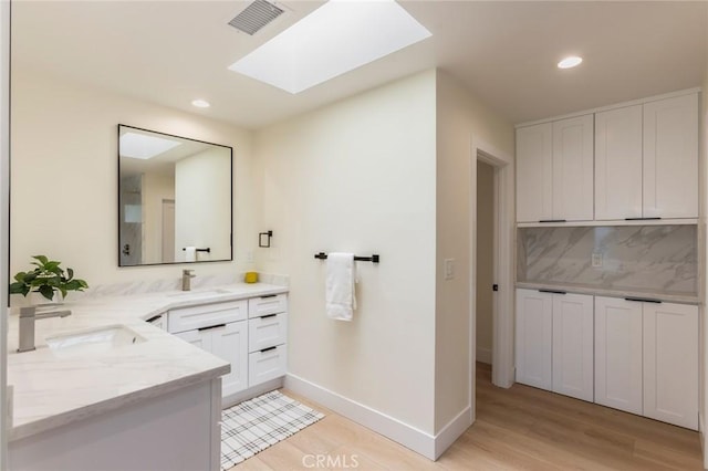 34693 Camino Capistrano Unit B, Dana Point, CA 92624 - bathroom with wood finished floors, vanity, a skylight, tasteful backsplash, and recessed lighting
