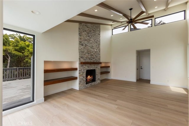34693 Camino Capistrano Unit B, Dana Point, CA 92624 - unfurnished living room featuring ceiling fan, a fireplace, light wood-type flooring, beam ceiling, and a towering ceiling