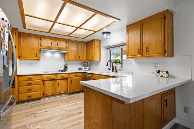 7009 Etter St, Bakersfield, CA 93308 - kitchen with stainless steel appliances, a peninsula, brown cabinets, light wood-style flooring, and decorative backsplash