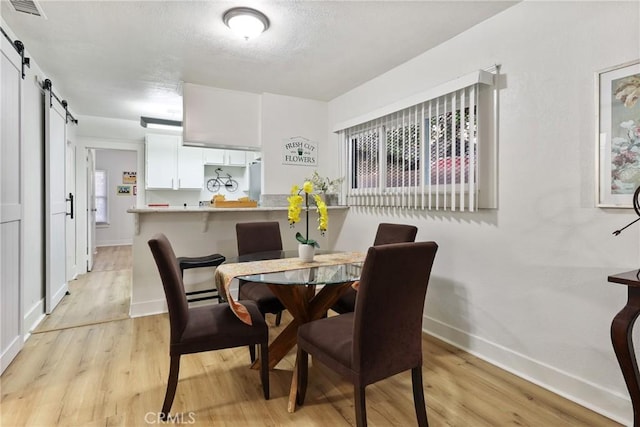 1146 N Loma Vista Dr, Long Beach, CA 90813 - dining area featuring a barn door, light wood-style floors, and healthy amount of natural light