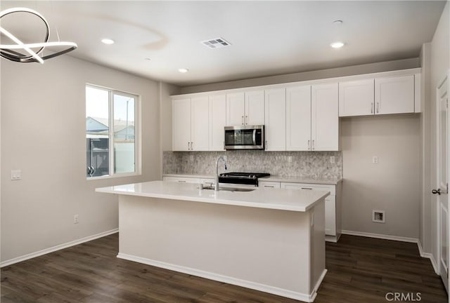 31844 Gimbal Way, Winchester, CA 92596 - kitchen featuring stainless steel microwave, decorative backsplash, white cabinets, a kitchen island with sink, and recessed lighting