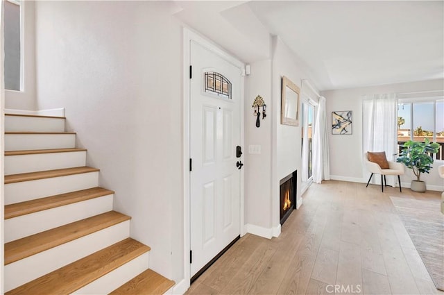 881 Calle Pluma, San Clemente, CA 92673 - entrance foyer with stairway, light wood finished floors, and a warm lit fireplace