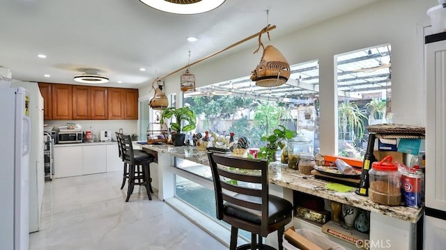 17230 San Lorenzo Cir, Fountain Valley, CA 92708 - kitchen featuring freestanding refrigerator, stainless steel microwave, brown cabinets, healthy amount of natural light, and recessed lighting