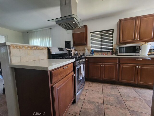 4434 Crocker St, Los Angeles, CA 90011 - kitchen with stainless steel appliances, island range hood, light countertops, decorative backsplash, and light tile patterned flooring