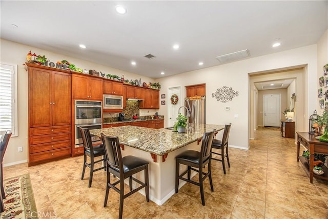1506 Pierce Ml, Beaumont, CA 92223 - kitchen featuring stainless steel appliances, a kitchen bar, an island with sink, light stone countertops, and recessed lighting