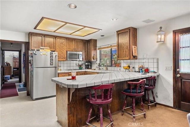 625 La Bonita Ct, Chico, CA 95973 - kitchen featuring appliances with stainless steel finishes, decorative backsplash, a peninsula, brown cabinetry, and recessed lighting
