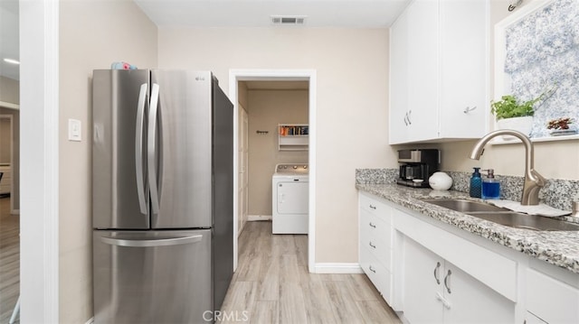 2648 N G St, San Bernardino, CA 92405 - kitchen featuring freestanding refrigerator, washer / dryer, white cabinetry, light wood finished floors, and light stone counters