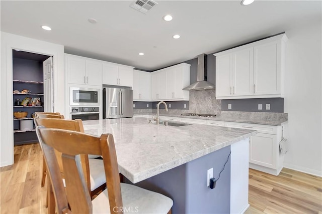 32469 Peters St, Menifee, CA 92584 - kitchen with wall chimney exhaust hood, appliances with stainless steel finishes, a breakfast bar, recessed lighting, and white cabinets