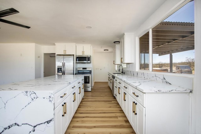 5655 Last Mile Rd, Johnson Valley, CA 92285 - kitchen with stainless steel appliances, light wood-style floors, white cabinetry, and light stone counters